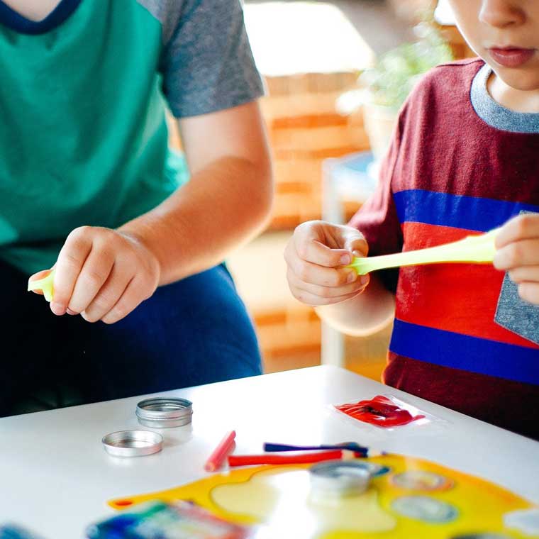 Two children mixing putty at a table.